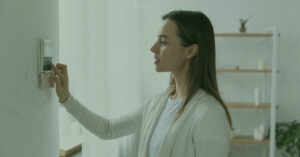 woman setting heat temperature on home thermostat